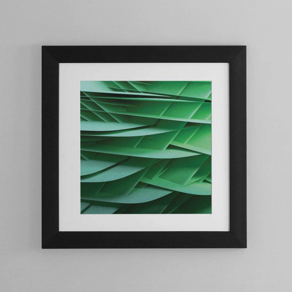 Abstract wall art resembling many sheets of intersecting green paper. Hung on a living room wall.